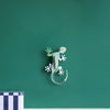 Decorative lizard wall art on a green wall with a striped box at the bottom.